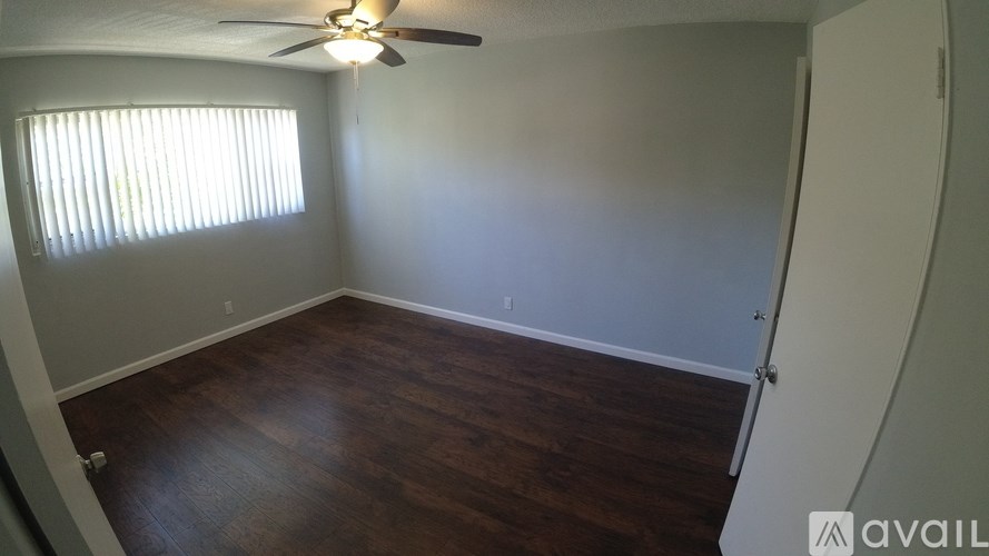 A room with a ceiling fan and wooden flooring.