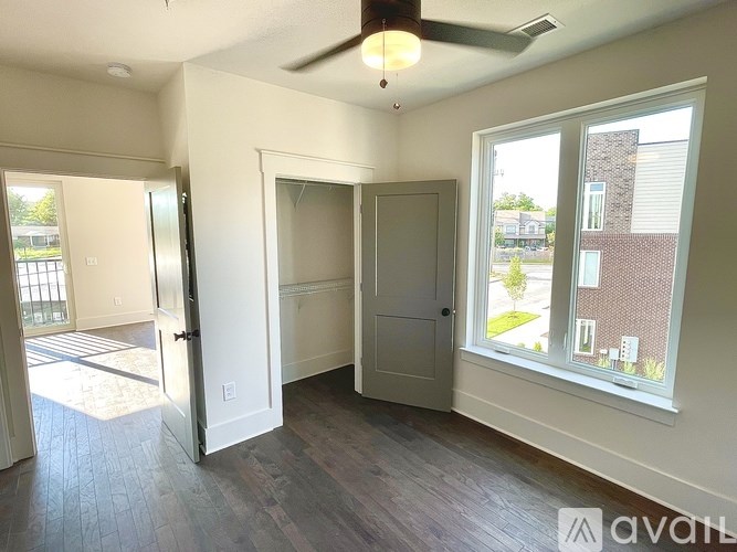 A room with a ceiling fan and a window overlooking a street.