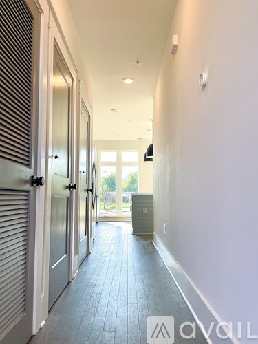 A long hallway with a door on the left and a window on the right.