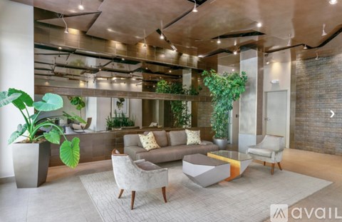 A modern living room with a grey sofa set and a large potted plant.