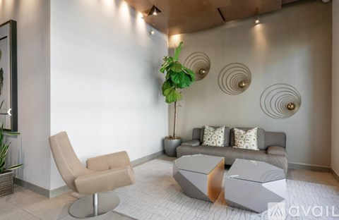 A living room with a grey couch, a beige armchair, and a plant.