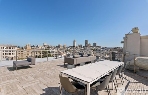 A rooftop patio with a table and chairs overlooking a city skyline.