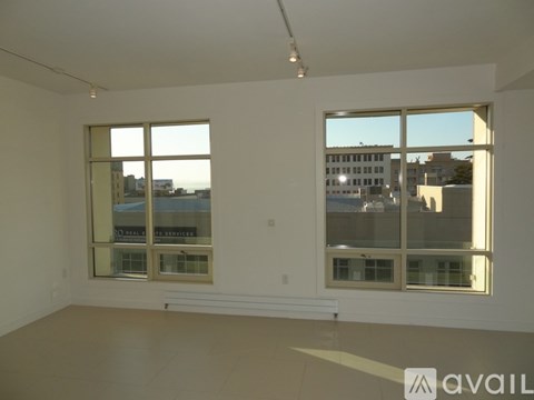 A large empty room with two windows looking out onto a cityscape.
