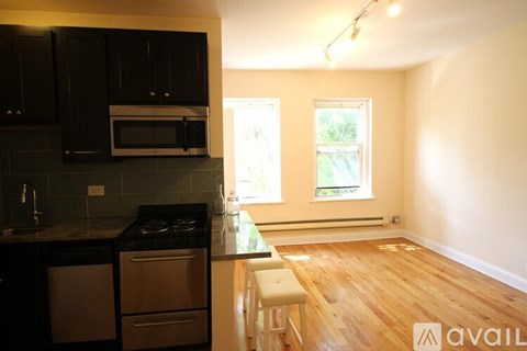A kitchen with black cabinets and a wooden floor.