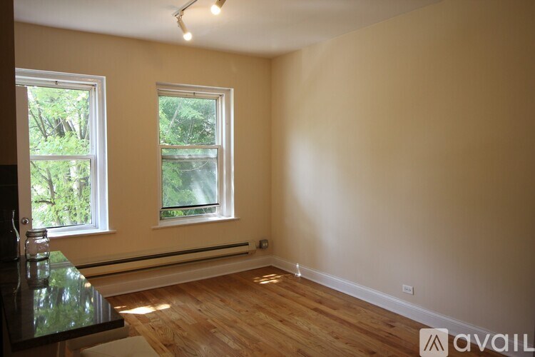 A room with wooden floors and two windows.