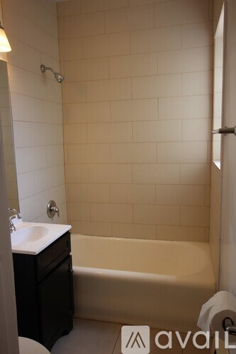 A bathroom with a white tub, sink, and tiled walls.