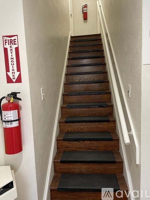 A staircase with a fire extinguisher and a fire exit sign on the wall.