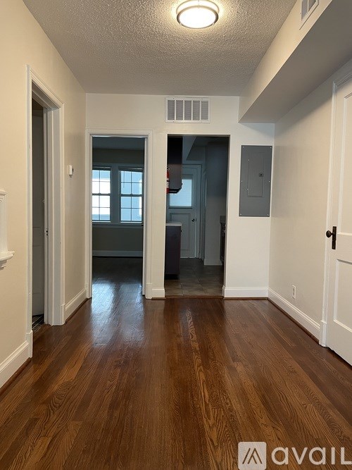 A hallway with wood flooring and white walls.