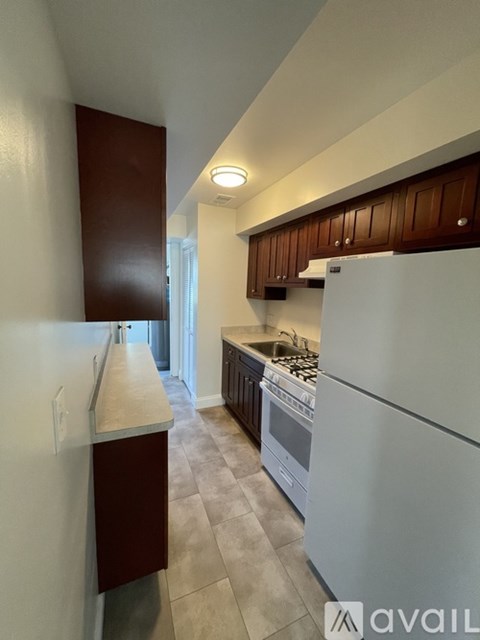 A kitchen with a white refrigerator and brown cabinets.