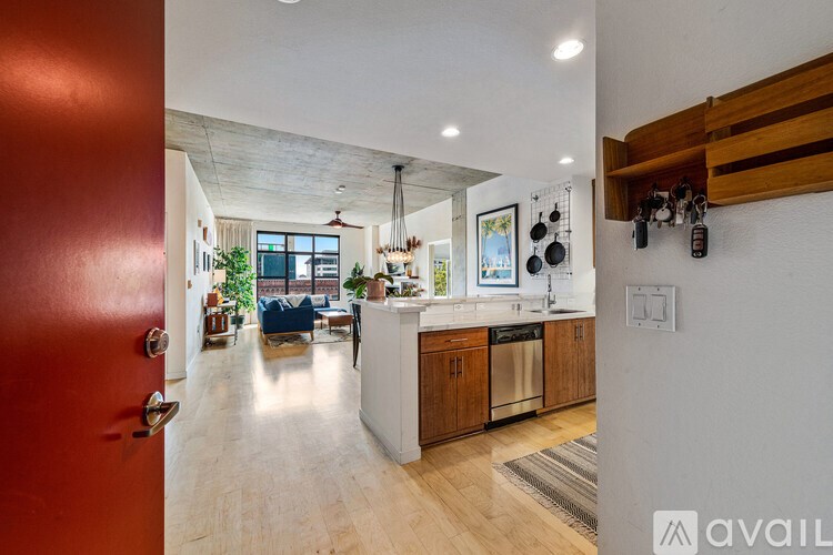 A modern kitchen with wooden cabinets and a red door.