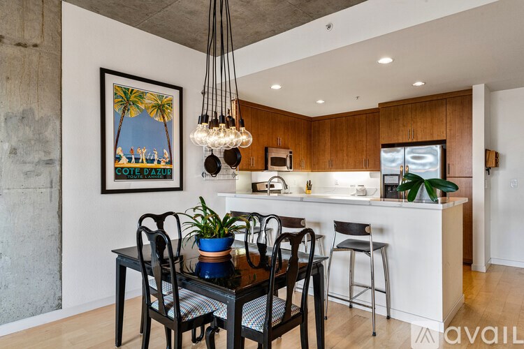 A kitchen with a dining table and chairs and a framed picture of a beach scene on the wall.