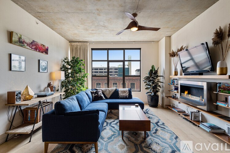 A living room with a blue sofa and a ceiling fan.