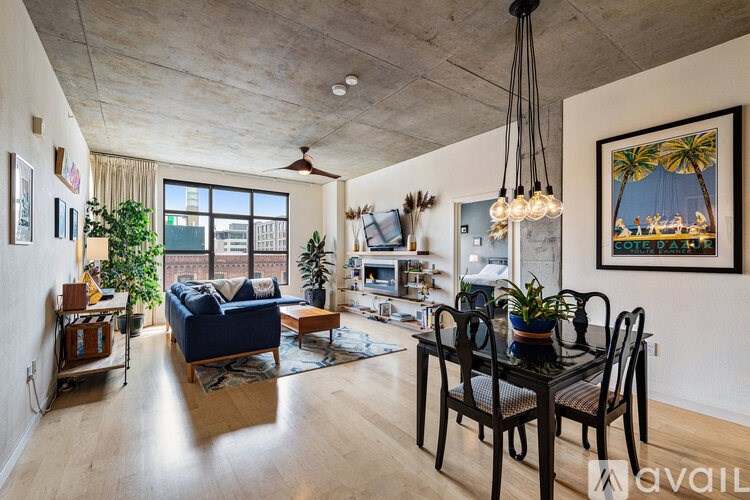 A living room with a blue couch and a dining table with chairs.