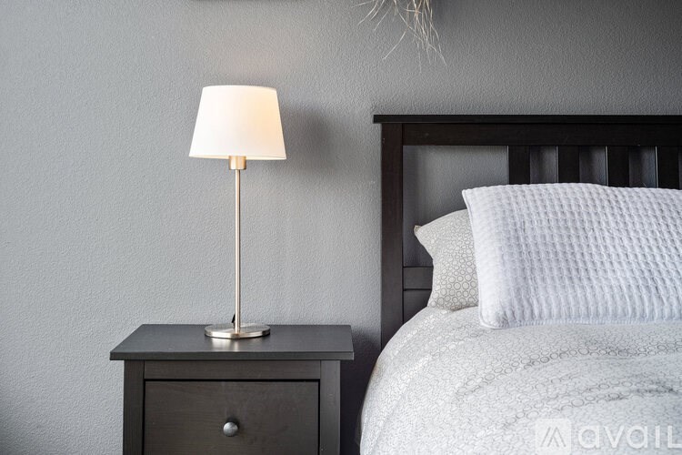 A bedroom with a bed, nightstand, and lamp.