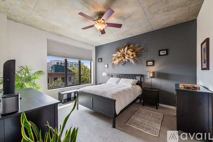 A bedroom with a bed, nightstand, and a ceiling fan.