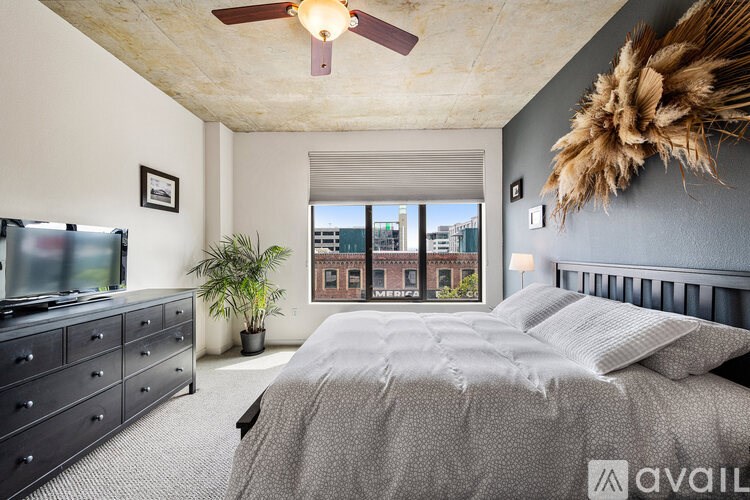 A bedroom with a large bed, a dresser, and a ceiling fan.