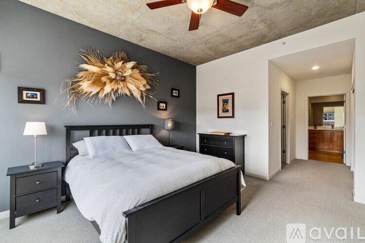 A bedroom with a large bed, a ceiling fan, and a nightstand with a lamp.