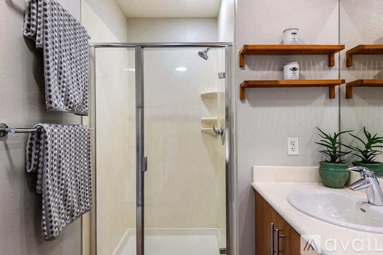 A bathroom with a shower, sink, and towel rack.