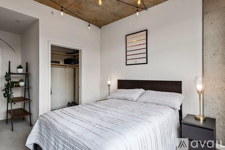 A bedroom with a bed, a lamp, and a shelf with plants.
