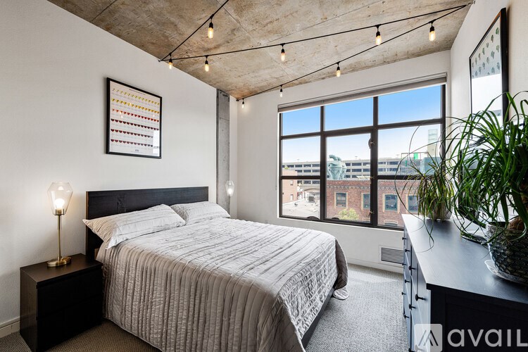 A bedroom with a large bed and a window overlooking a cityscape.