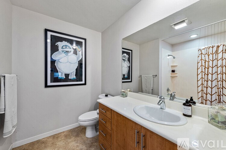 A bathroom with a white toilet, a sink, and a framed picture on the wall.