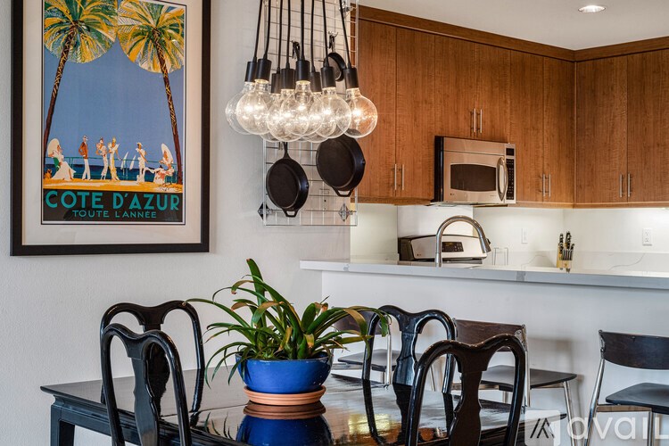 A dining room with a table, chairs, and a poster on the wall.