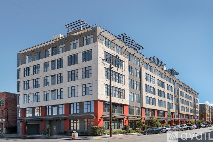 A modern multi-story building with a parking lot in front.