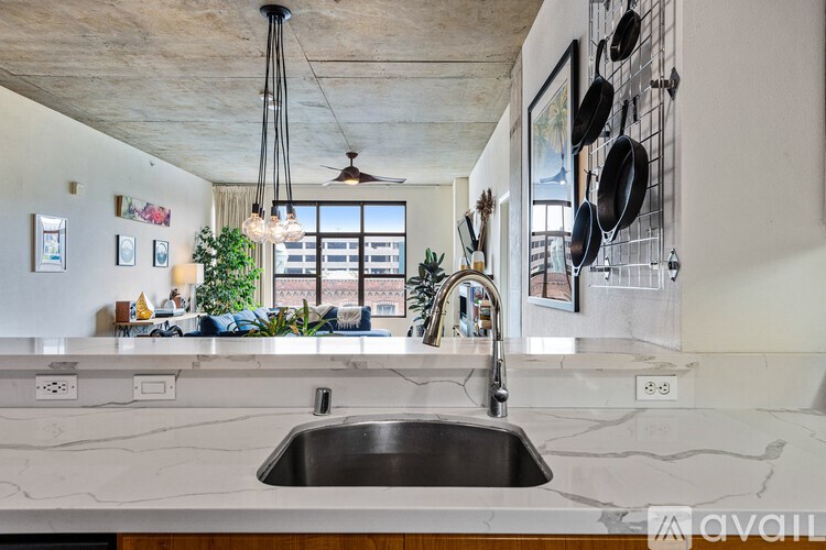 A kitchen with a marble countertop and a stainless steel sink.