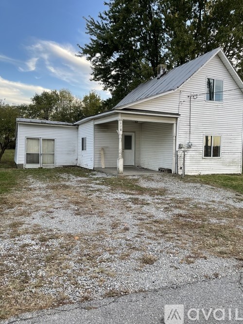 A white house with a gravel driveway in front.