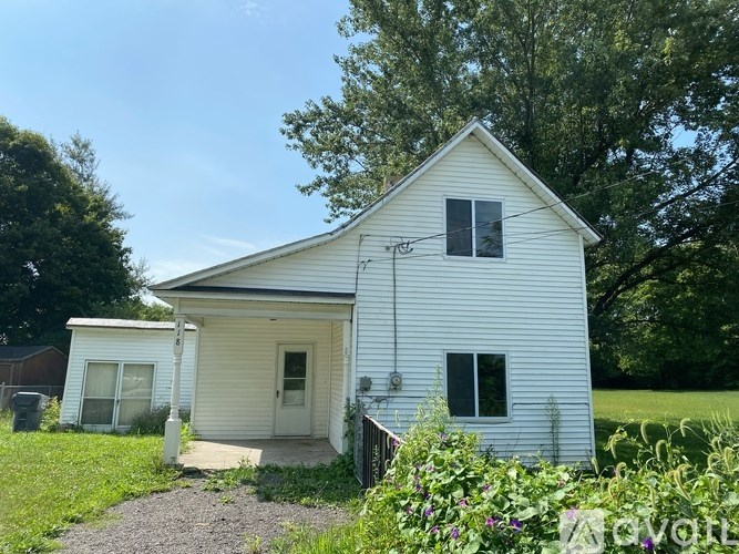 A white house with a gravel driveway in front of it.
