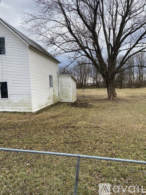 A white house with a tree in front of it.