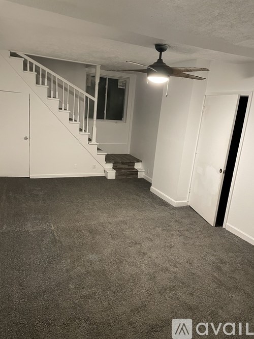 A room with a staircase and a ceiling fan.