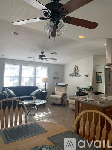 A living room with a couch, chairs, and a ceiling fan.