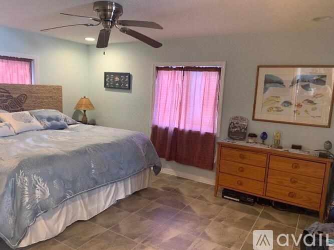 A bedroom with a bed, a dresser, and a ceiling fan.