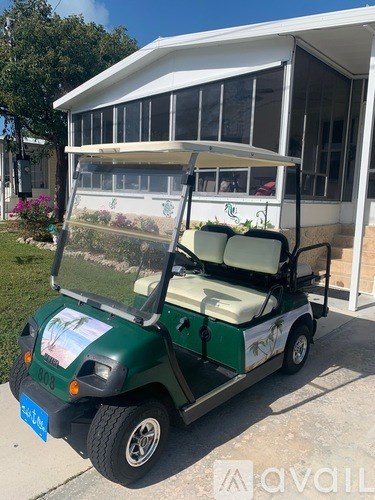 A green golf cart with a white roof is parked in front of a house.