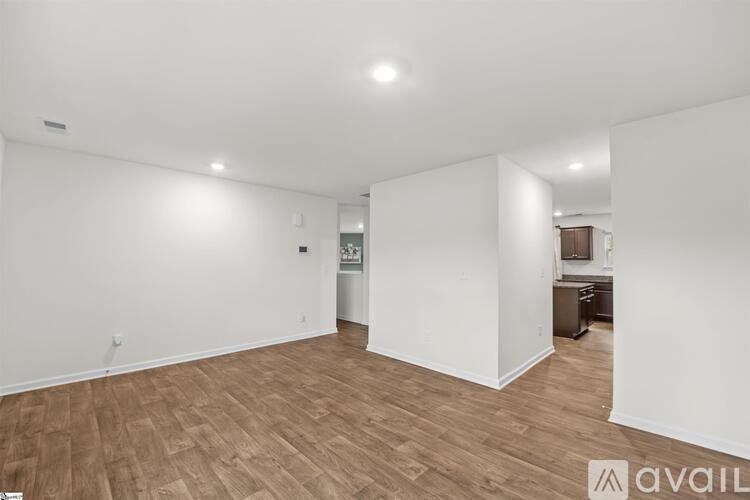 A spacious room with wooden flooring and white walls.