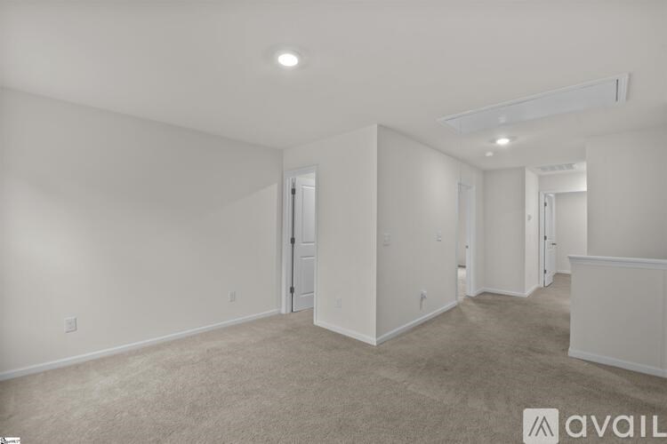 A spacious room with carpeted floor and white walls.