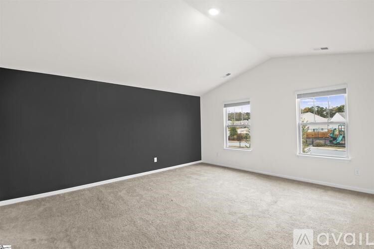 A spacious room with a carpeted floor and two windows.