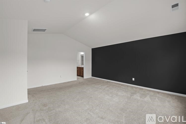 A spacious room with a carpeted floor and a door on the right side.