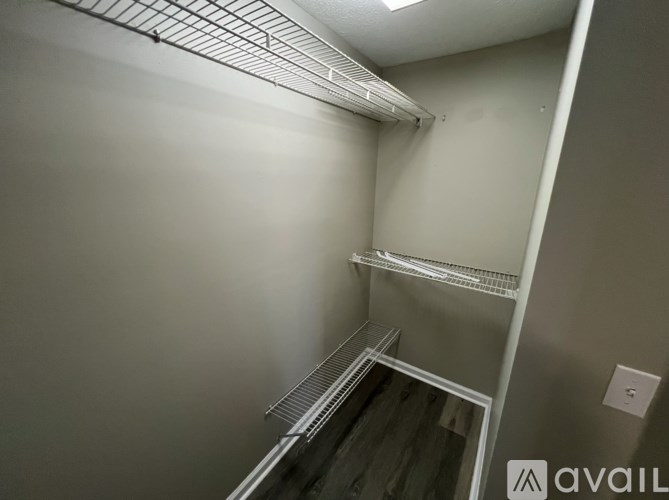 A small, empty room with a metal shelving unit and a wooden floor.