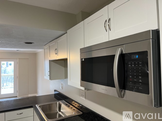 A modern kitchen with a stainless steel microwave above a sink.