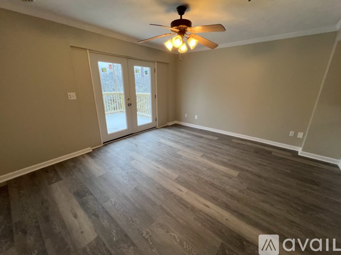 A room with a ceiling fan and sliding glass doors.