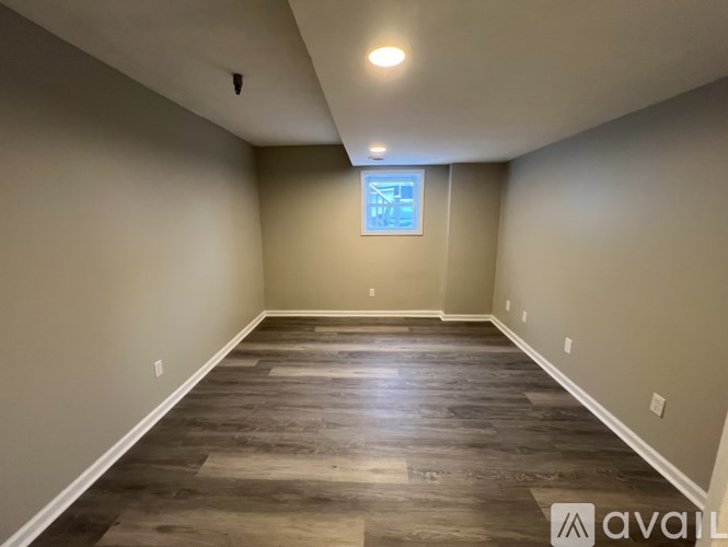 A room with wooden flooring and a window with a blue frame.