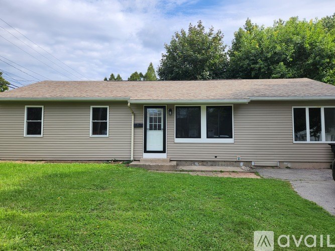A house with a green lawn and trees in the background.