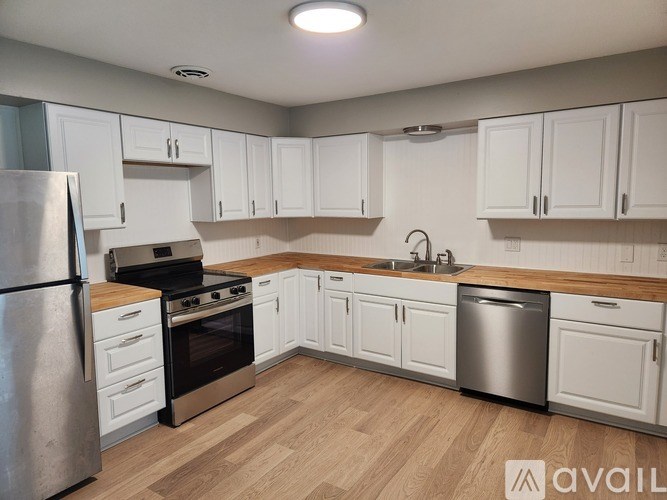 A kitchen with white cabinets and a wooden countertop.