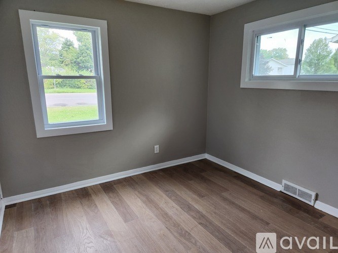 A room with two windows and wooden flooring.