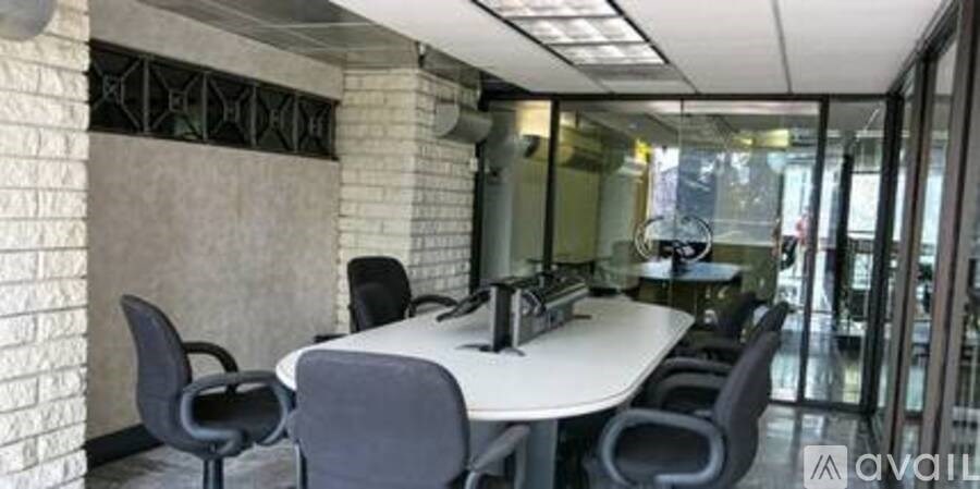 A conference room with a white table and black chairs.