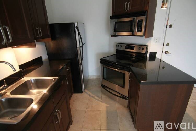 A kitchen with a black refrigerator, stove, and microwave.