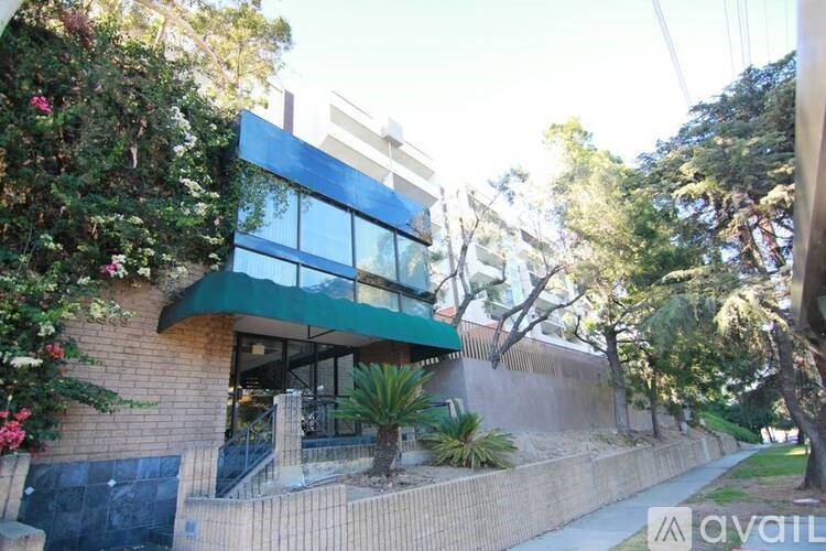 A modern house with a green awning and a garden in front.