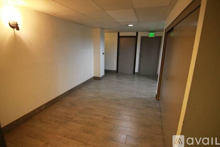 A hallway with a light on the wall and doors at the end.